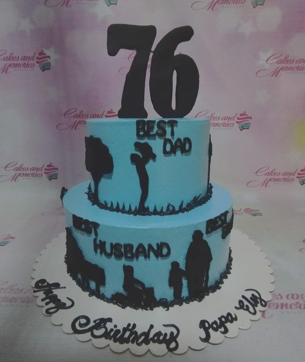 Light blue 2-tier birthday cake for a 76th birthday featuring black silhouette toppers of a father and family with 'Best Dad' and 'Best Husband' text.