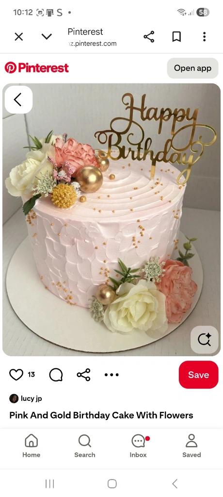 Pink textured soft icing birthday cake with fresh flowers, gold spheres, and a gold Happy Birthday topper.