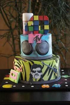 2-tier 80s themed cake with MTV logo, boombox speakers, zebra print, cassette tape, and Pac-Man decorations.