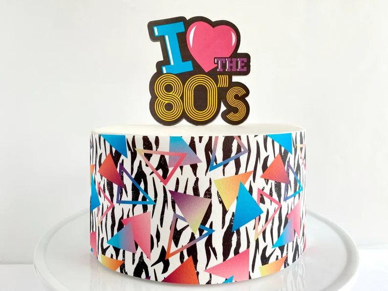 Retro 80s themed cake with zebra print sides, neon geometric triangles, and an I Love the 80s topper.
