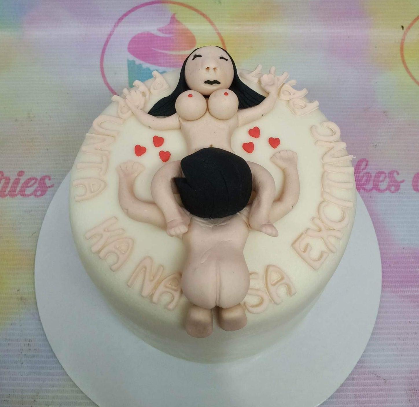 A humorous adult-themed cake featuring 3D fondant figures of a couple in an intimate pose with red hearts and a Tagalog message.