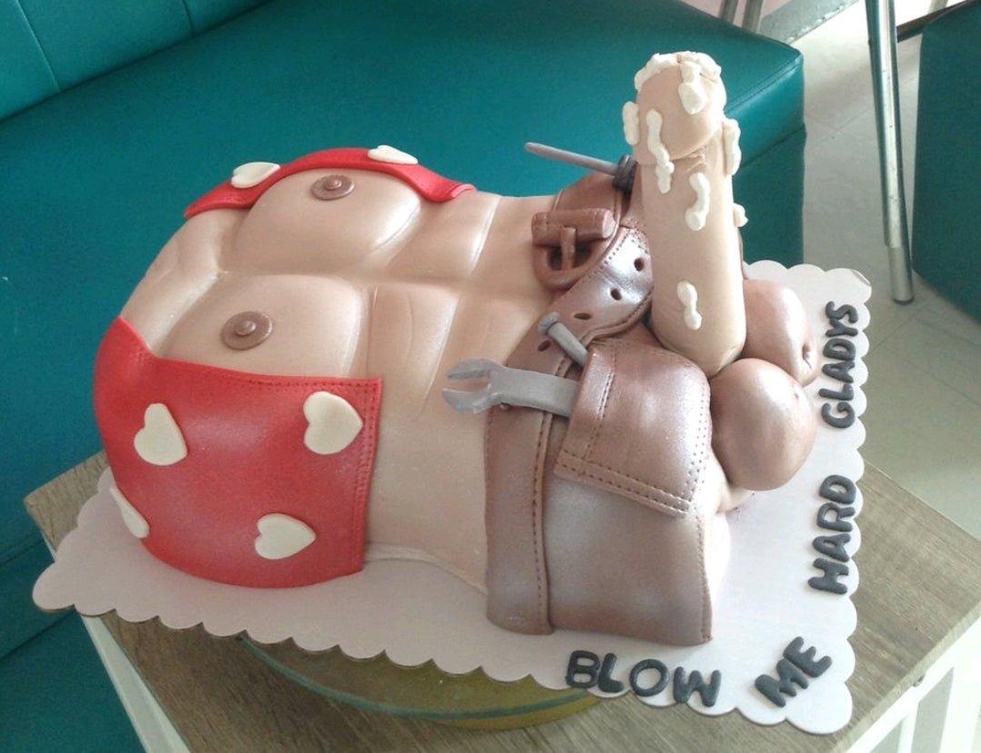 A humorous adult-themed cake shaped like a muscular male torso with a 3D fondant phallic topper and tool belt.