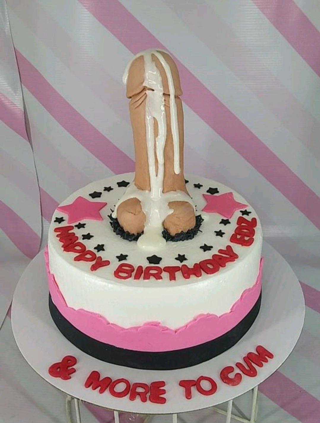 White and pink birthday cake featuring a large tan fondant phallic topper with white icing drip and red lettering.