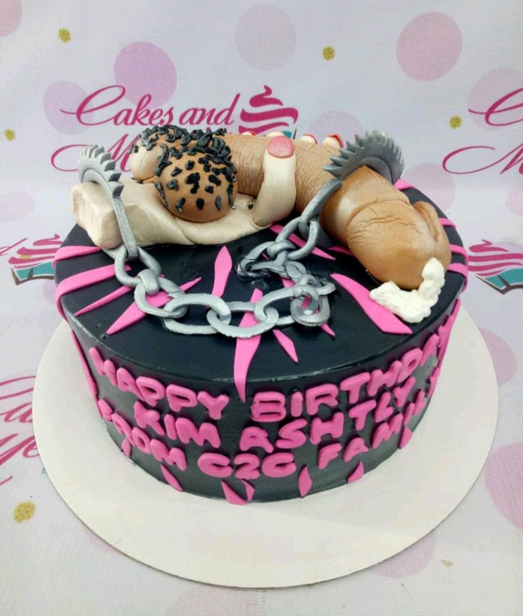 Black and pink adult themed birthday cake with a large 3D fondant figure, silver chains, and pink icing spikes.