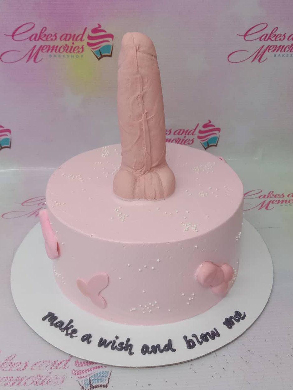 Pink minimalist cake with a large flesh-colored anatomical topper and white sprinkles.