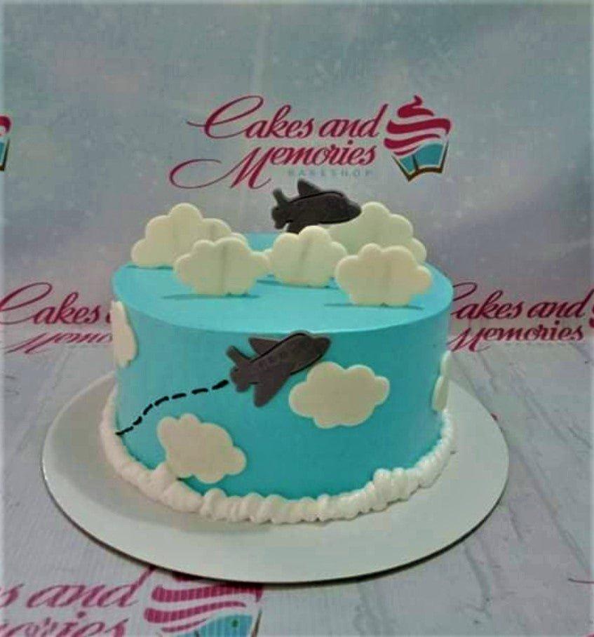 Light blue airplane themed cake with white fondant clouds and dark gray airplane toppers