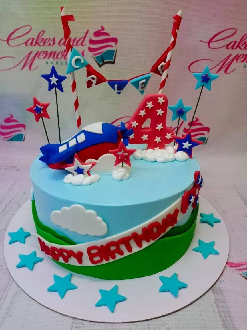 Blue and green airplane themed birthday cake with a red number 4 topper, clouds, and stars.