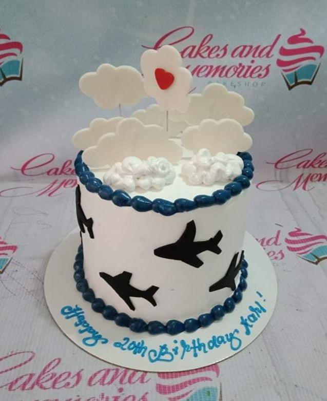White 1-tier birthday cake with black airplane silhouettes, blue icing borders, and white fondant clouds with a red heart.