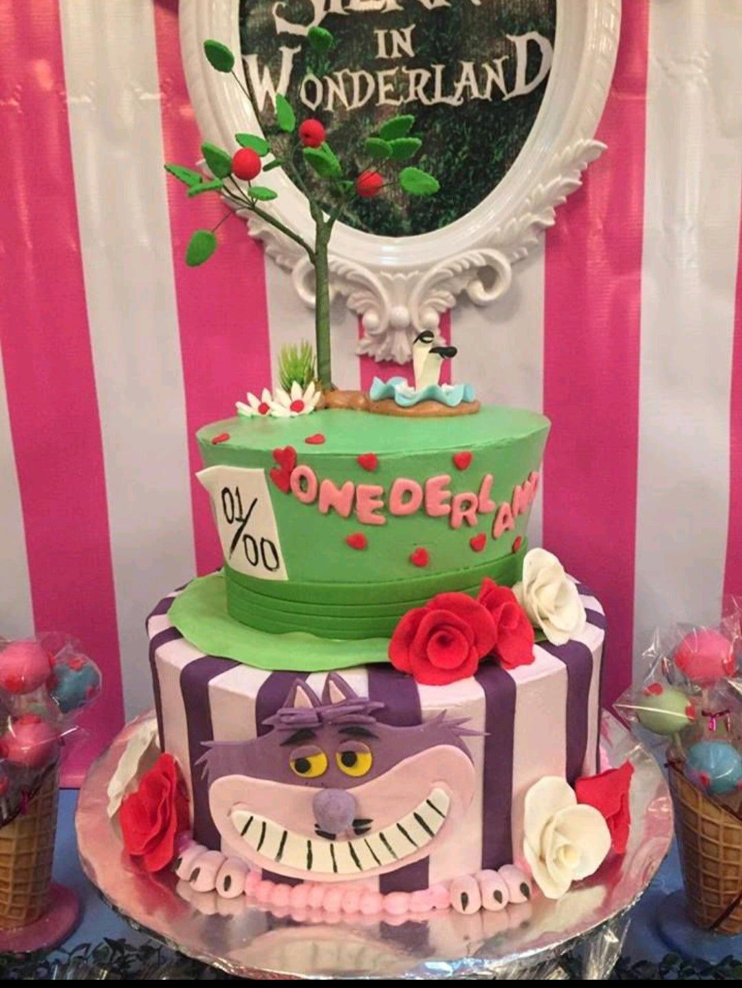 Alice in Wonderland themed 2-tier cake featuring Cheshire Cat and Mad Hatter hat designs with a fondant tree topper.