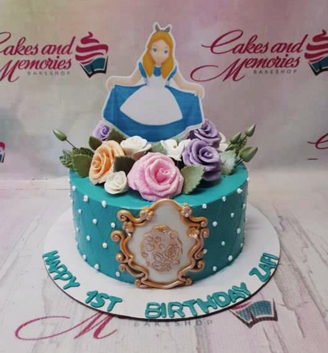 Teal Alice in Wonderland themed cake with colorful gumpaste roses and a character printout topper.