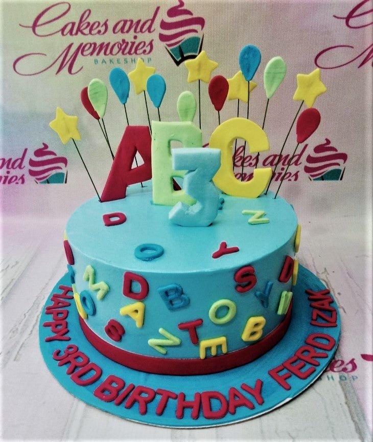 Light blue alphabet and numbers birthday cake with colorful fondant letters and balloon toppers for a 3rd birthday celebration.
