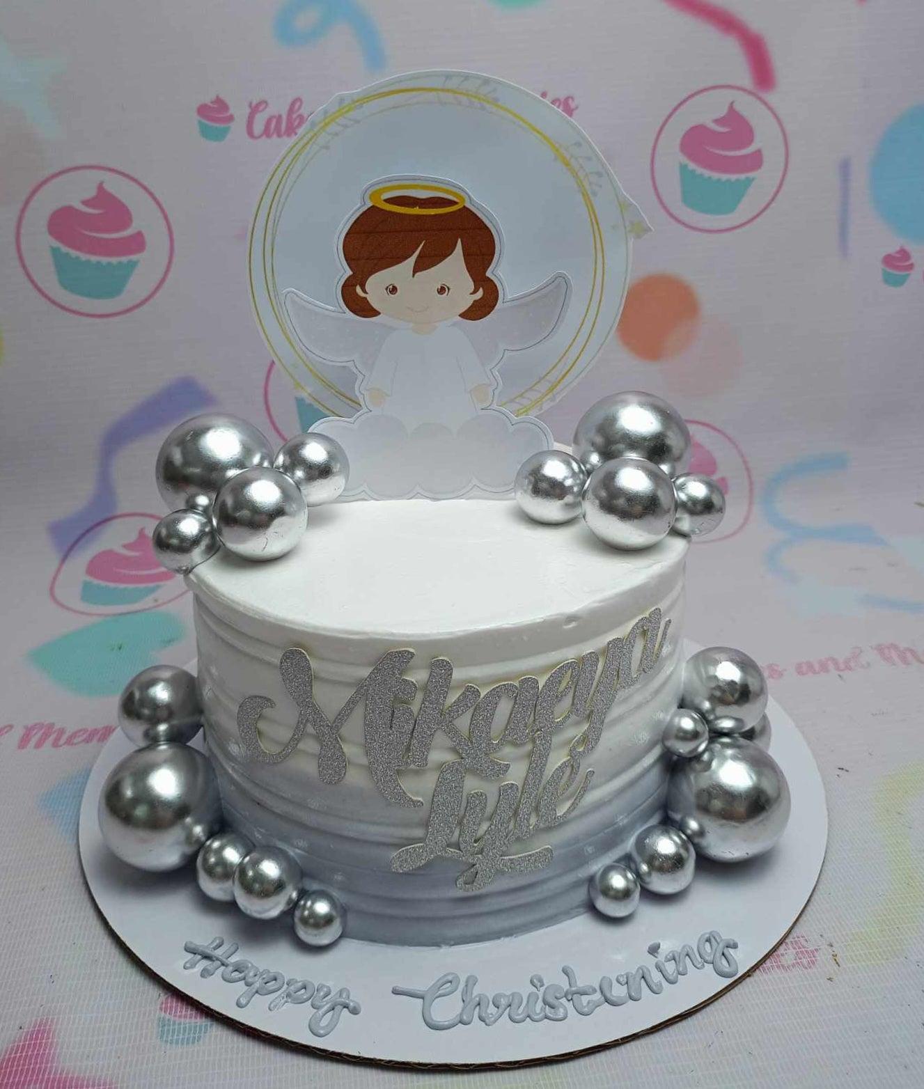 White and gray gradient christening cake with a cute angel printout topper and silver decorative spheres.
