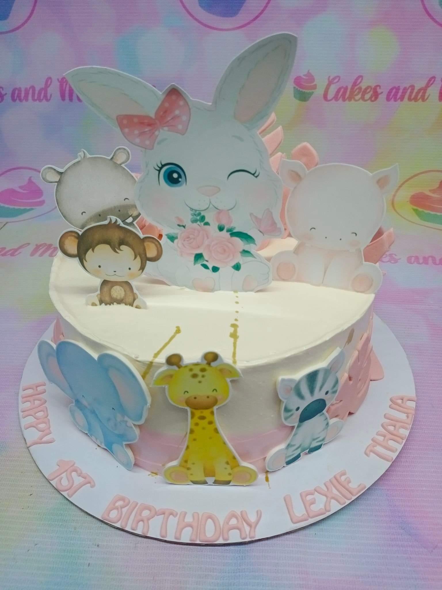 White 1-tier animal safari birthday cake with a large bunny, monkey, hippo, elephant, giraffe, and zebra printouts.