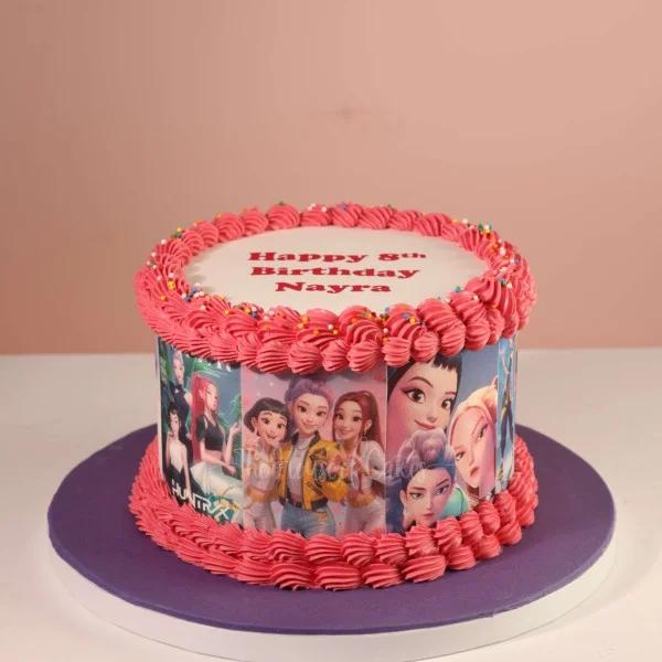 Pink 1-tier birthday cake featuring printed anime-style characters on the sides with pink icing rosettes and colorful sprinkles.