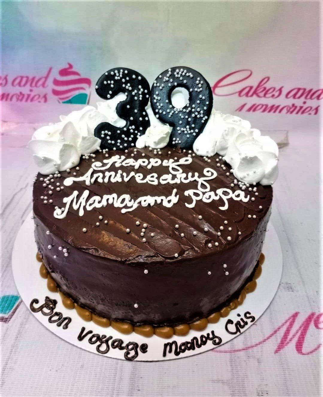 Chocolate anniversary cake with white icing rosettes, silver dragees, and a black number 39 topper.