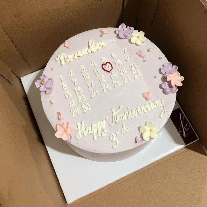 Lavender bento cake with a hand-piped November calendar design, pink and purple icing flowers, and a Happy Anniversary message.