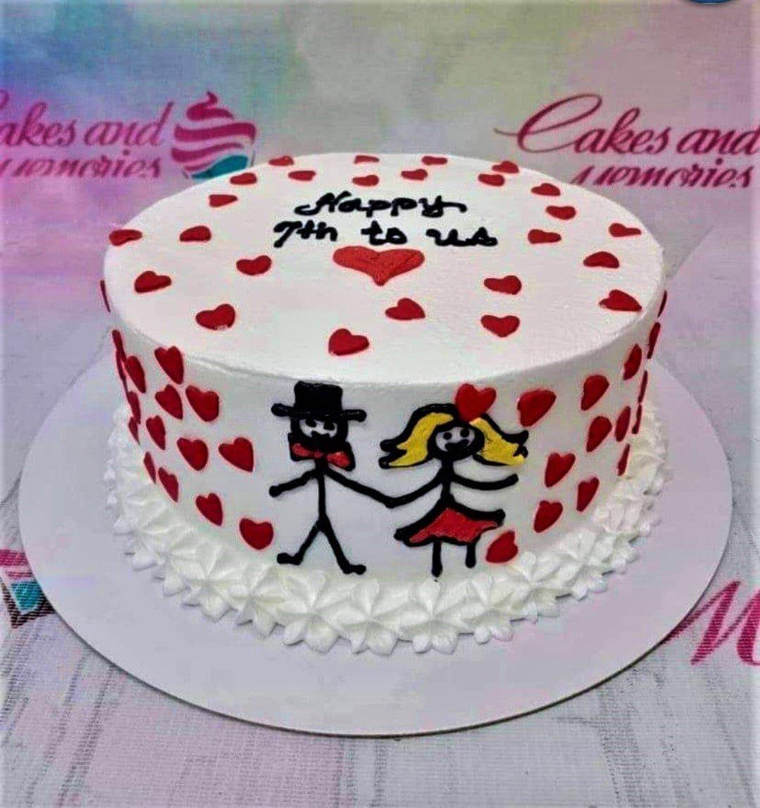 White minimalist anniversary cake with red heart icing decorations and a hand-drawn stick figure couple holding hands.