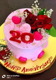 Pink anniversary cake with red roses, baby's breath, pink hearts, and a red number 20 topper on a gold base board.