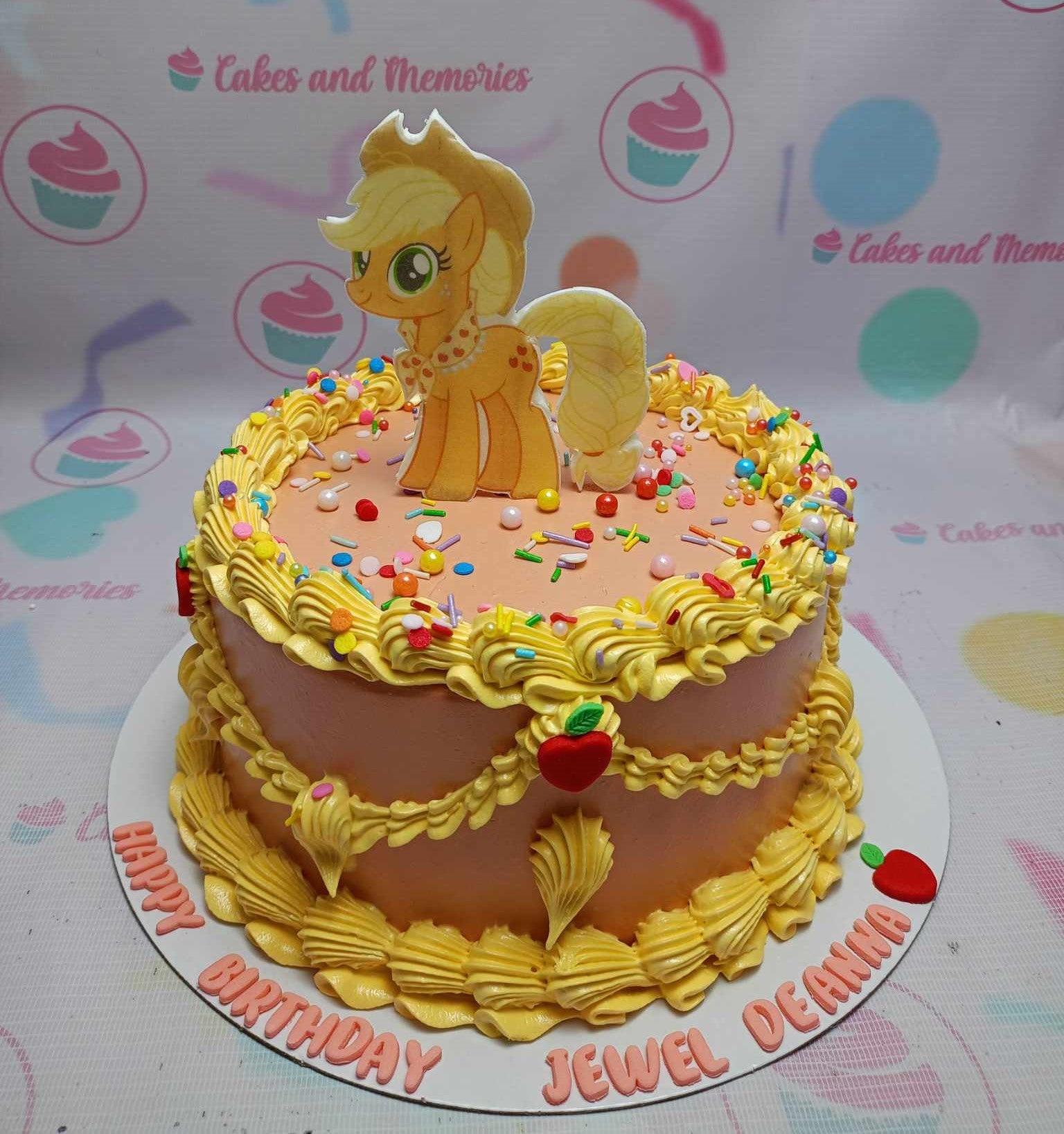Orange My Little Pony Applejack birthday cake with yellow icing ruffles, sprinkles, and red fondant apples.