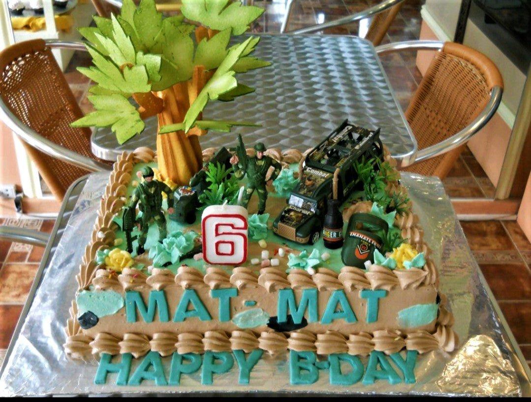 Army themed rectangle cake with toy soldiers, military vehicles, a large tree topper, and a number 6 candle.