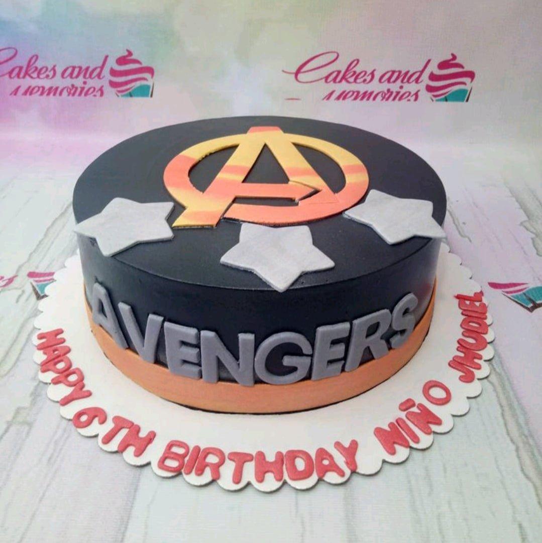 Black Avengers themed birthday cake with silver stars and a large orange and yellow Avengers logo on top.