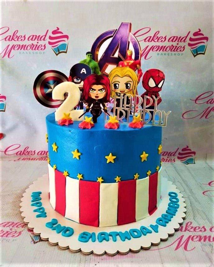 Avengers themed birthday cake with blue icing, red and white stripes, yellow stars, and superhero character toppers.