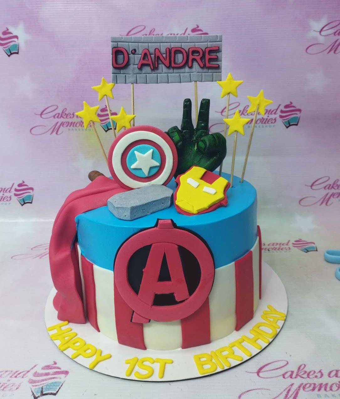 Avengers themed birthday cake with Captain America shield, Hulk fist, Iron Man mask, and Thor's hammer on blue and red fondant.