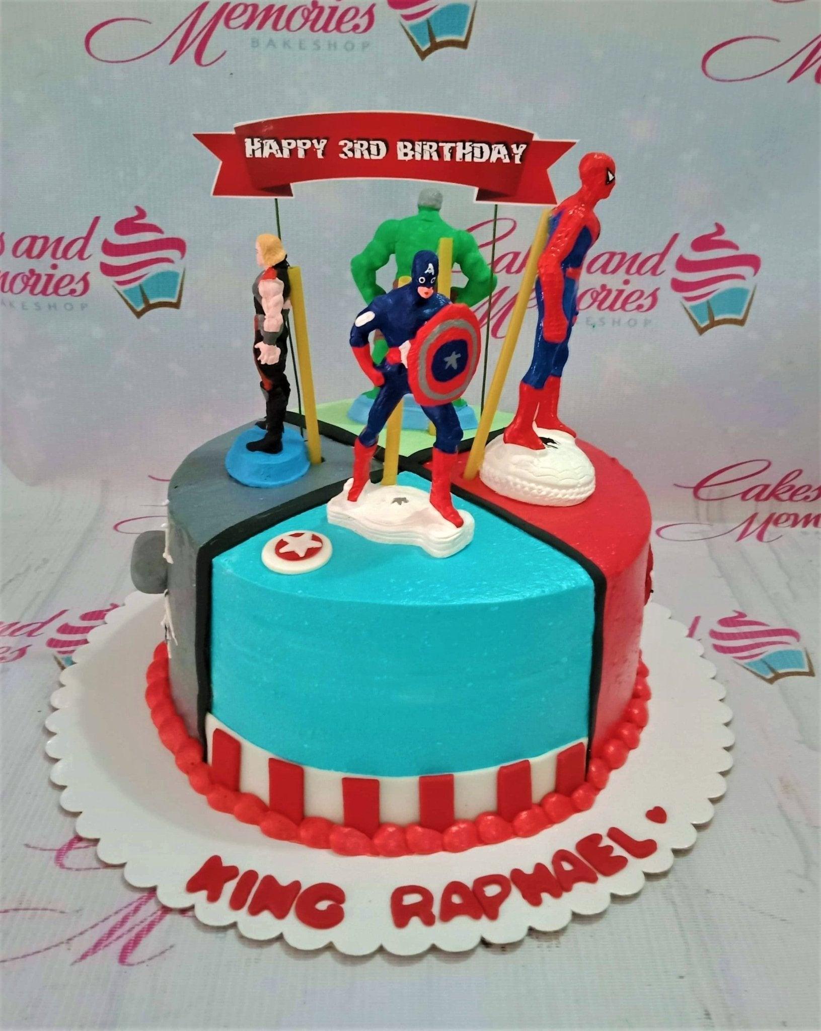 Avengers themed birthday cake with Captain America, Hulk, Thor, and Spiderman figurines on a multi-colored icing base.