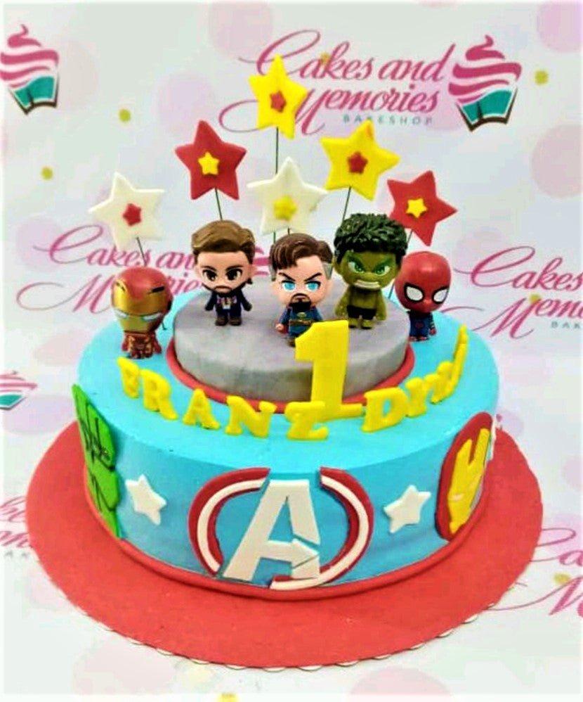 Avengers themed birthday cake with Iron Man, Hulk, Dr. Strange, and Spider-Man figurines on a light blue base with superhero logos.