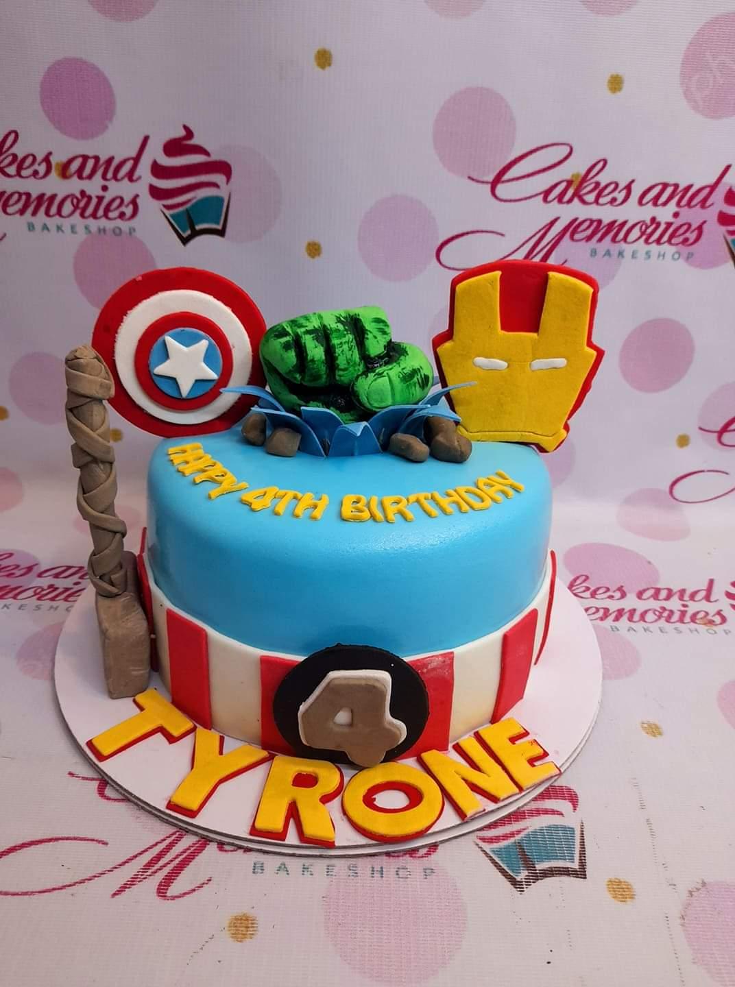 Avengers themed blue fondant cake with Hulk fist, Captain America shield, Iron Man mask, and Thor's hammer toppers.