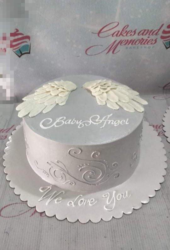Minimalist gray 1-tier cake with white gumpaste angel wings and piped icing swirls on the side.