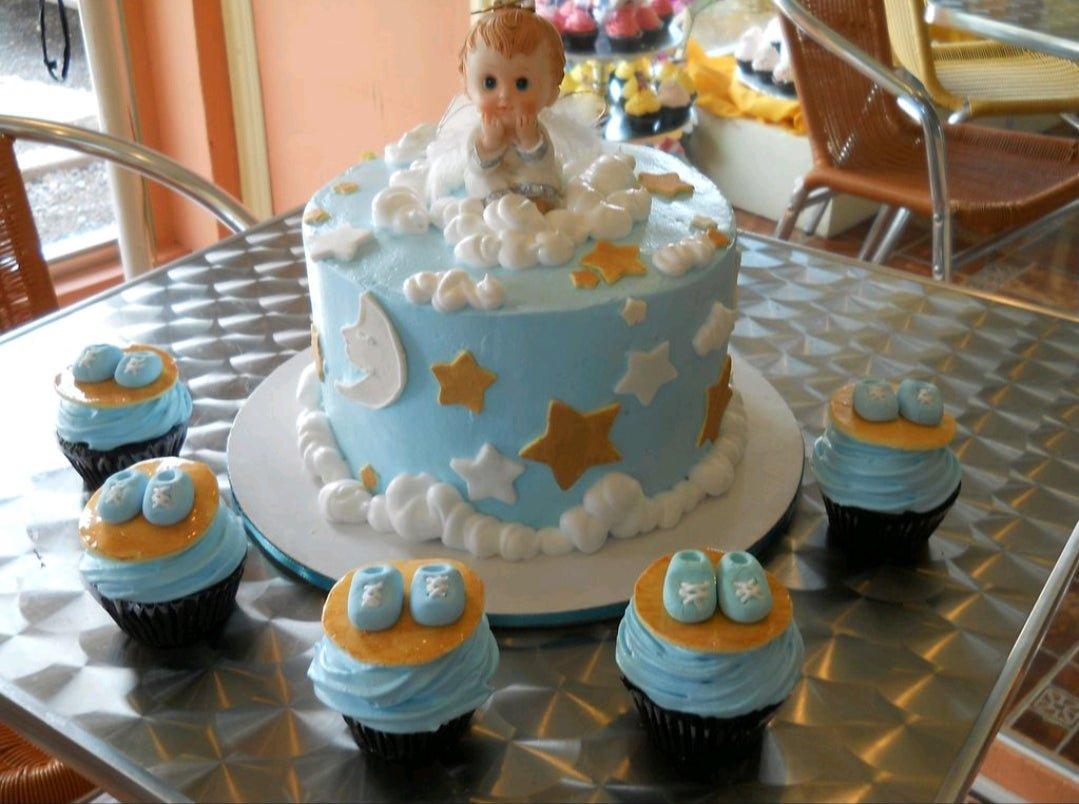 Light blue baby shower cake with a 3D baby angel topper, white icing clouds, and gold and white fondant stars.