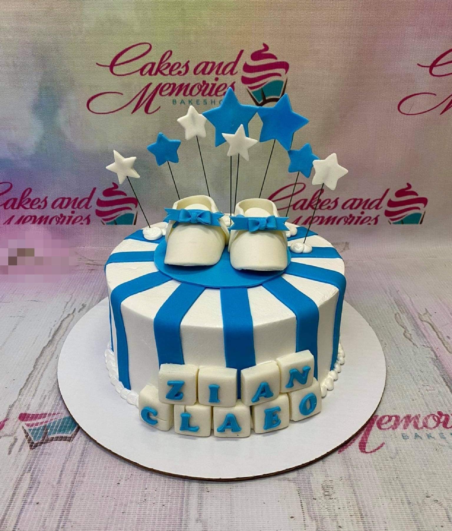 Blue and white striped baby boy cake with fondant baby shoes and star toppers