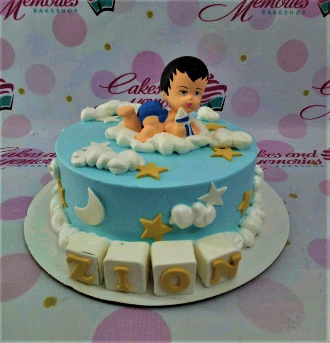 Light blue baby boy birthday cake with a 3D fondant baby topper on white clouds and gold stars.