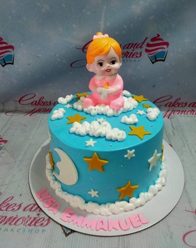 Light blue baby girl birthday cake with a 3D baby figurine, white icing clouds, and yellow fondant stars.