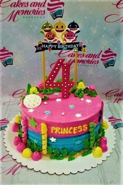 Pink and blue Baby Shark themed birthday cake with a large number 4 topper and character printouts.