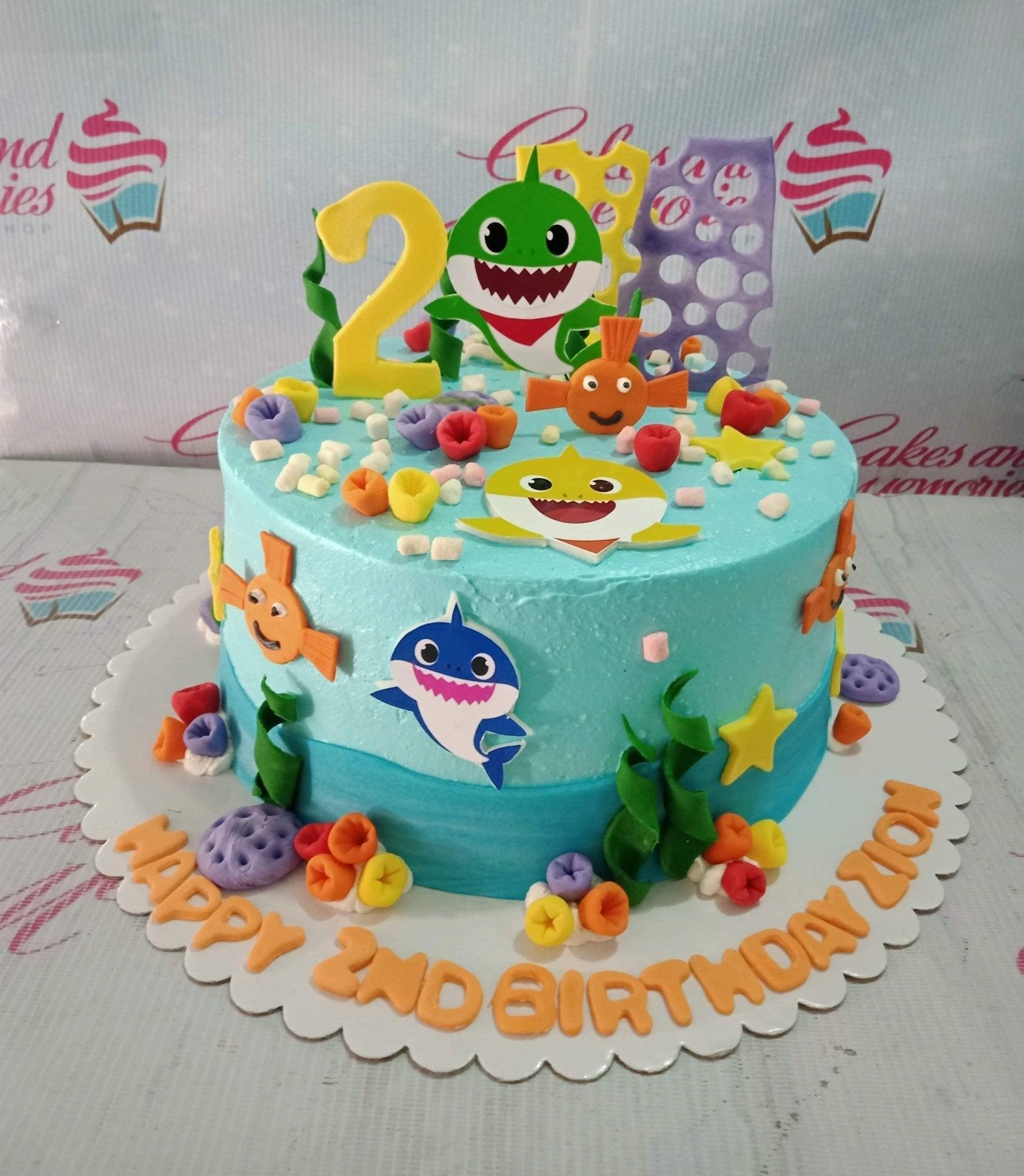 Baby Shark themed 1-tier blue cake with 3D fondant sea creatures and character printouts for a 2nd birthday.