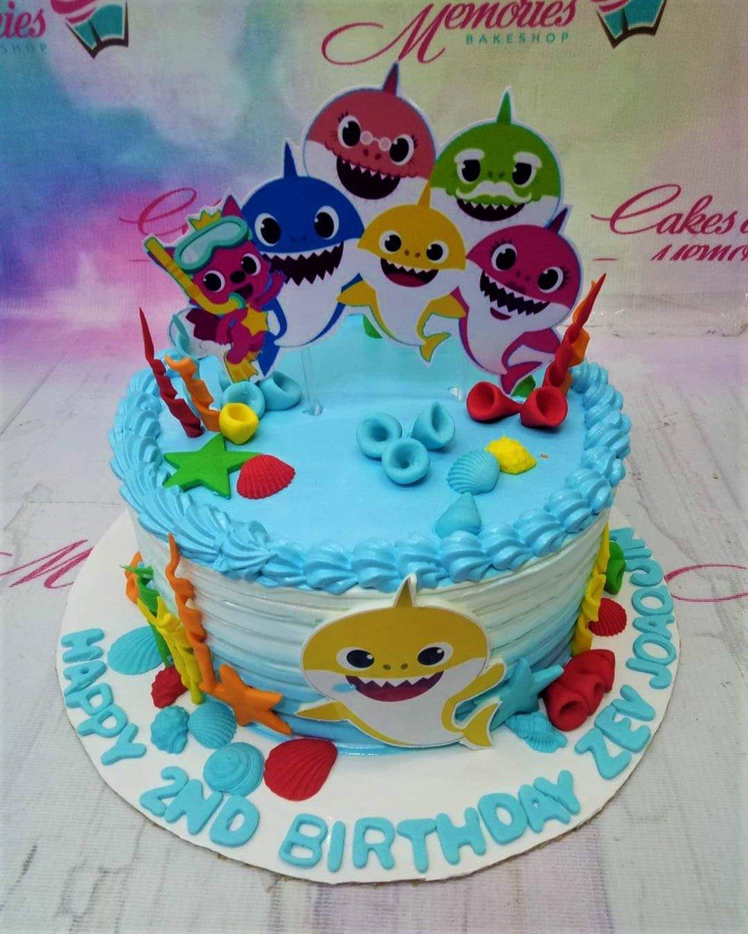 Light blue Baby Shark themed birthday cake with colorful gumpaste sea life and character printouts.