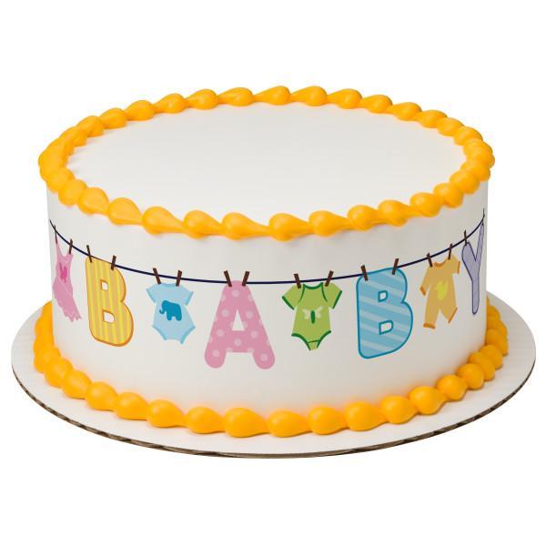 White round baby shower cake with yellow icing borders and a colorful baby clothesline printout design around the side.