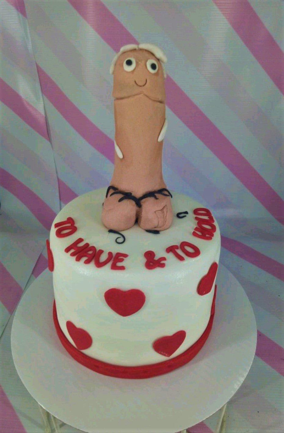 White fondant cake with red hearts and a humorous 3D flesh-colored figure on top for a bachelorette or adult celebration.