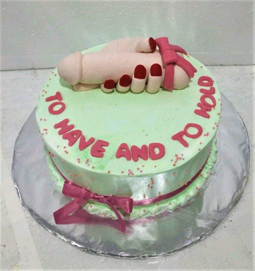 Light green bachelorette cake featuring a 3D fondant hand holding a phallic symbol with red nail polish and a pink bow.