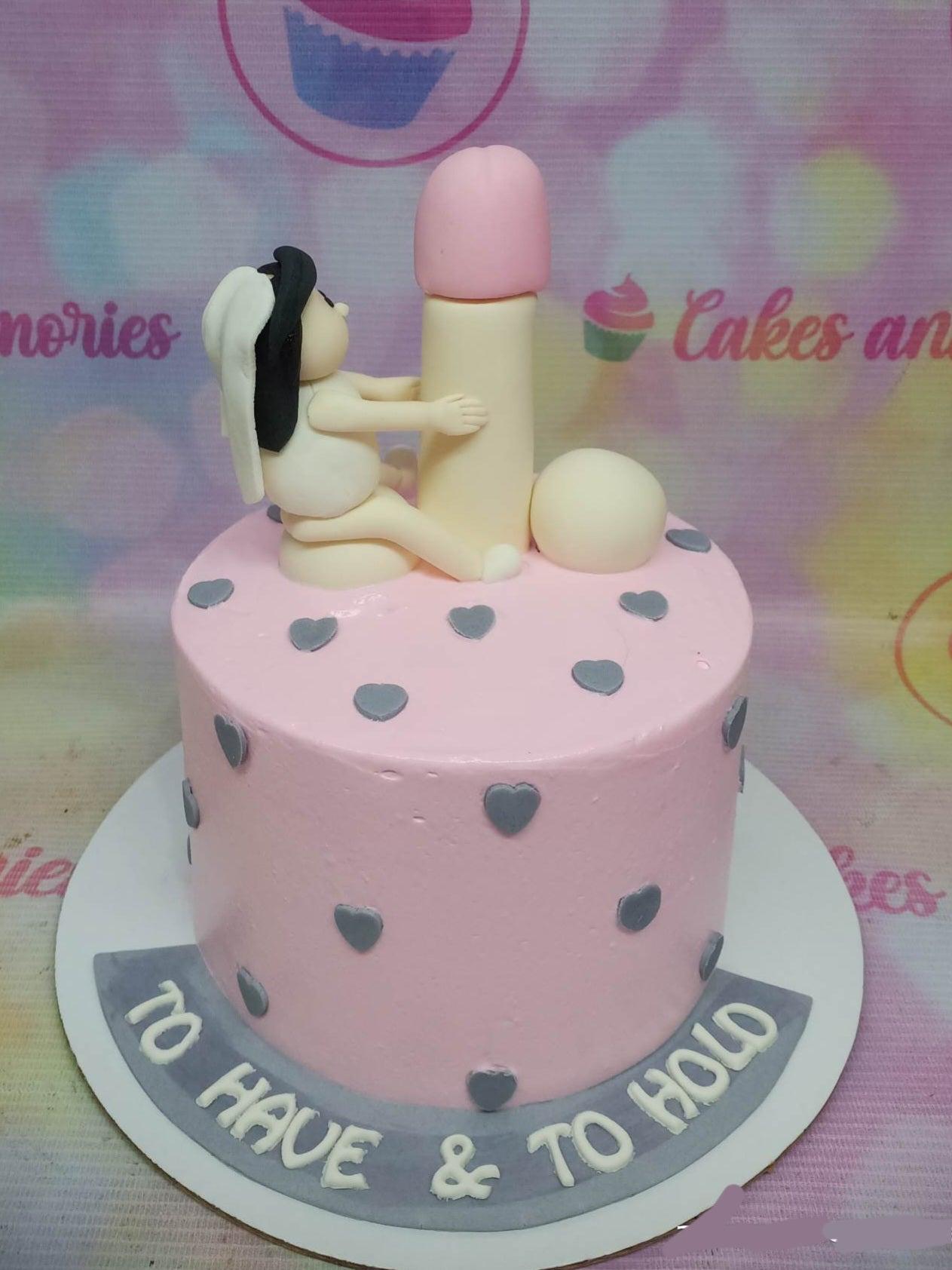 Pink bachelorette cake with a humorous 3D fondant bride figure hugging a large phallic topper and grey heart decorations.