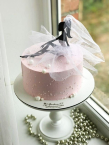 A pink 1 tier cake featuring a black ballerina silhouette and white pearl decorations.