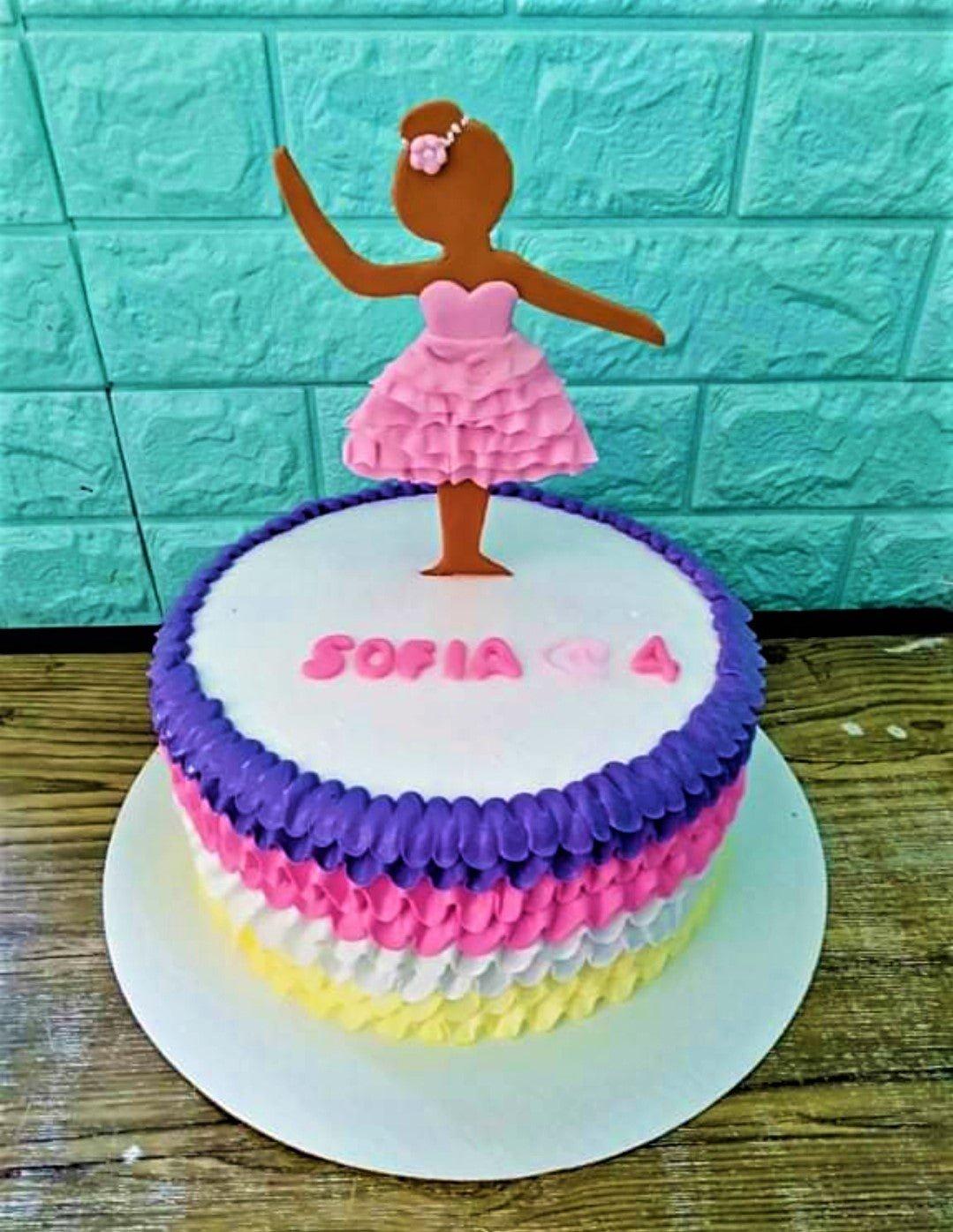Single tier ballerina birthday cake with colorful ruffled icing in purple, pink, white, and yellow, topped with a fondant ballerina figure.