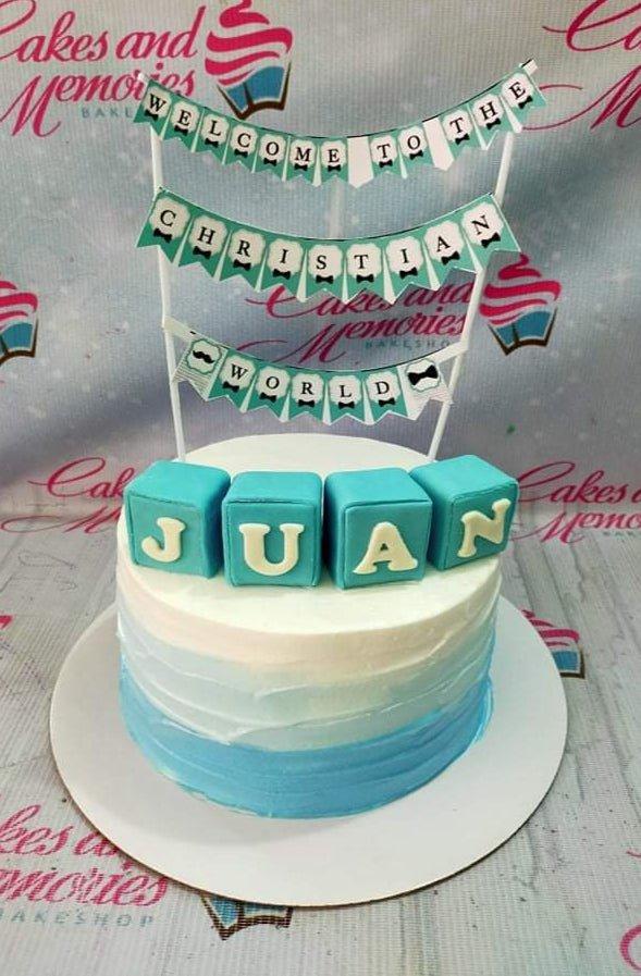 Blue and white ombre cake for a Christian world celebration with blue fondant name blocks and a banner topper.