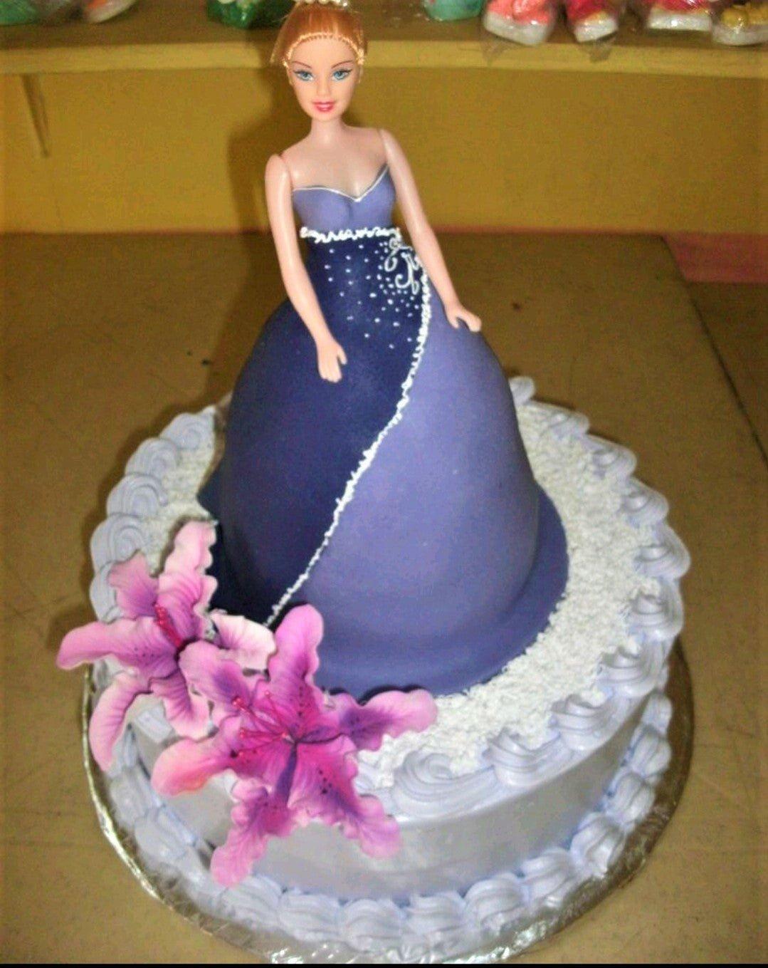 Purple doll cake with a Barbie topper wearing a dark purple fondant gown and pink gumpaste lilies on a light purple icing base.