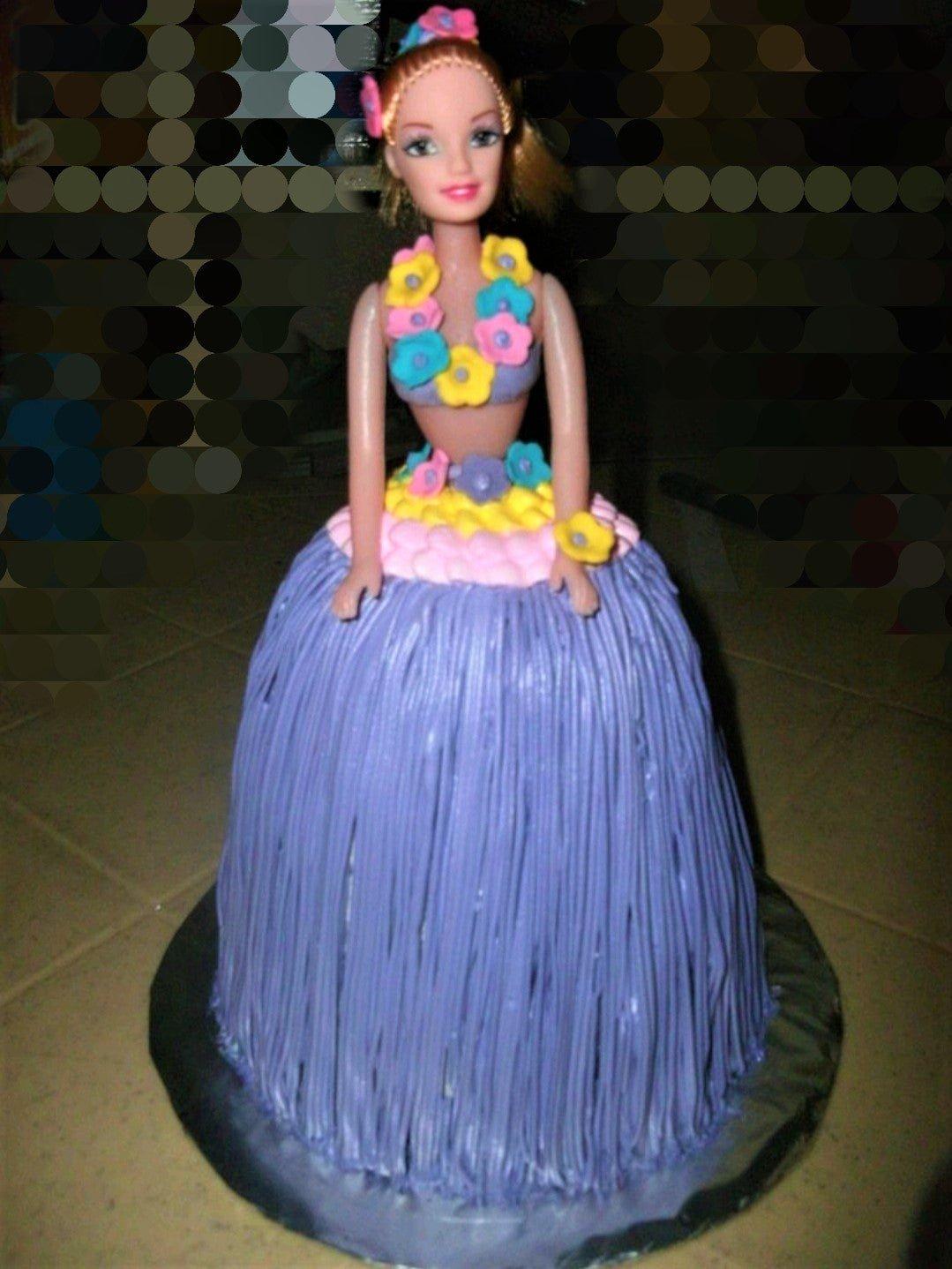 Barbie doll cake with a purple hula-style icing skirt and colorful fondant flower decorations.