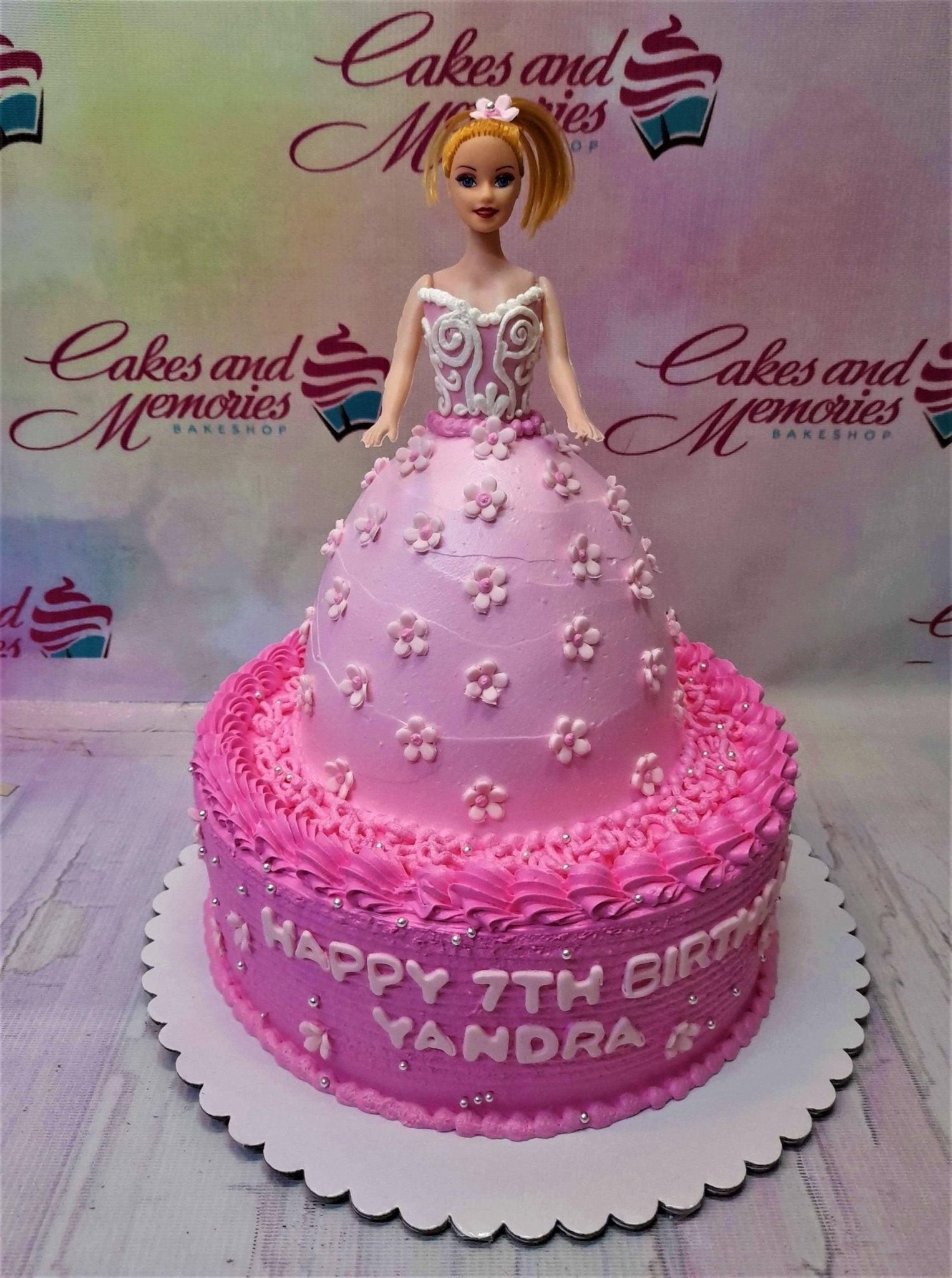 Pink Barbie doll dress cake with a tiered skirt design, floral icing details, and silver dragees for a 7th birthday celebration.