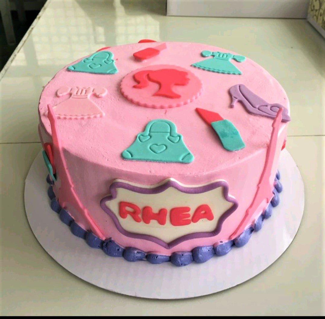 Pink Barbie themed cake with teal and purple fondant fashion accessories and a central Barbie silhouette.