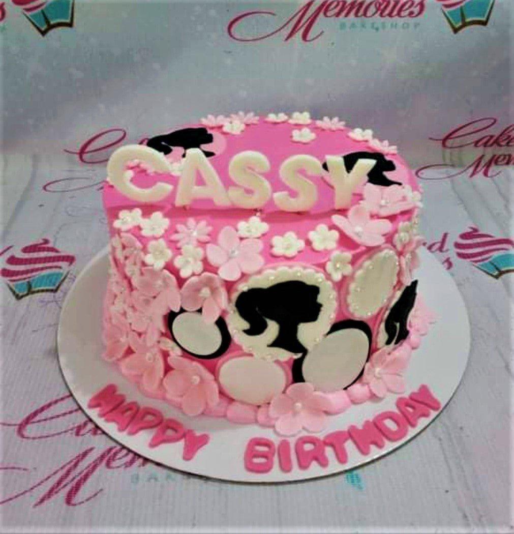 Pink Barbie themed birthday cake with white gumpaste flowers and black Barbie silhouettes on the side.